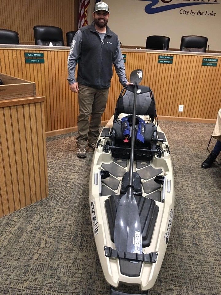 A kayak with fishing gear on display inside the library