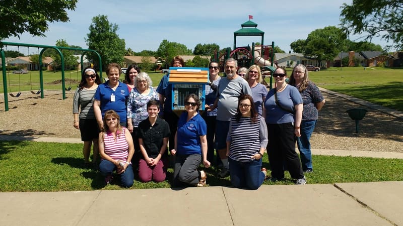 Library staff and volunteers standing with a Little Free Library
