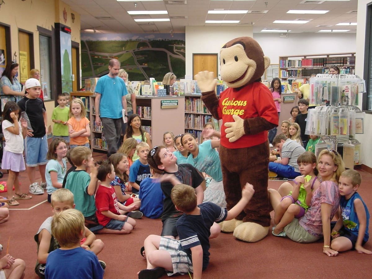 Children gathered on the floor for story time with a costumed character