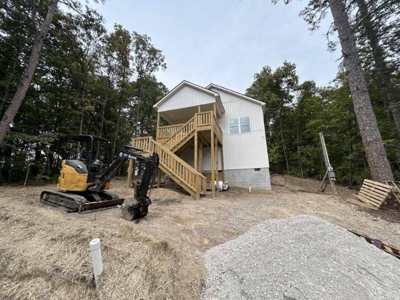 A mini excavator and a pile of gravel on the lot during site work